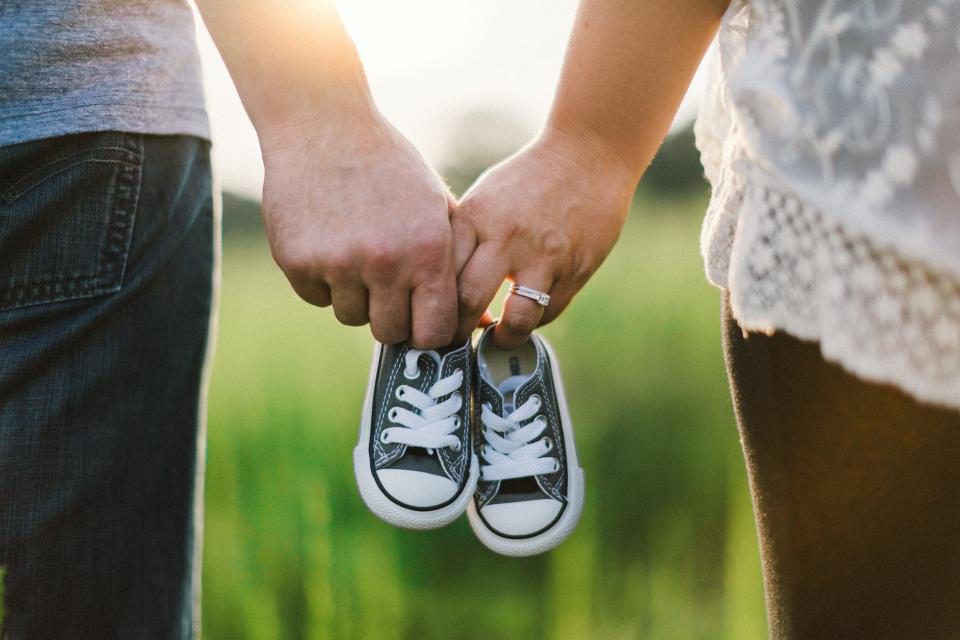 Ouders houden samen een paar kleine babyschoentjes vast